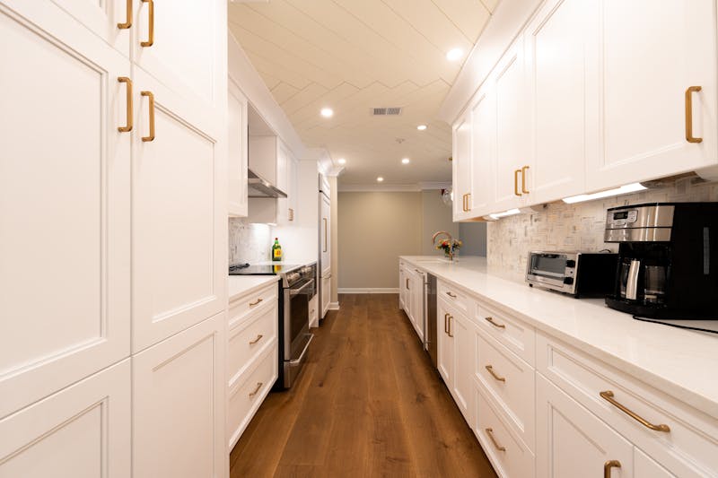 Modern white kitchen with hardwood flooring showing durable water resistant wood floor installation in a contemporary kitchen interior